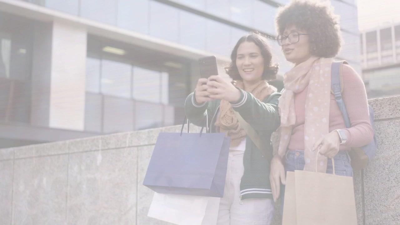 Due donne su un cornicione, la donna a sinistra tocca lo smartphone, condividendo gli acquisti, con etichette di vendita animate sullo schermo del telefono.