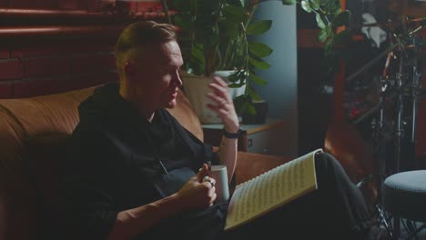 man reading music sheet in home music studio