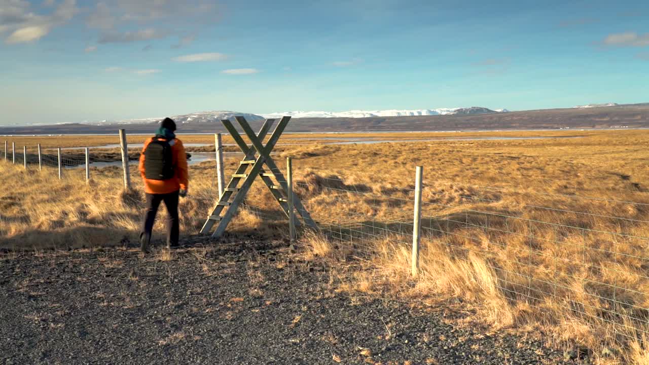 пеший турист взбирается по лестнице на ограду поля в солнечный день