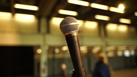 Micrófono-Vacío-Para-Cantar-O-Hablar-En-Eventos-En-El-Primer-Plano-Del-Escenario-En-Una-Sala-Vacía-Con-Luz-Amarillenta