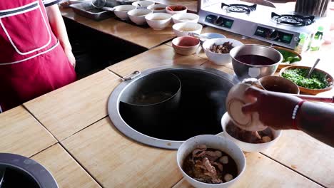 preparing noodle dish with meat and broth