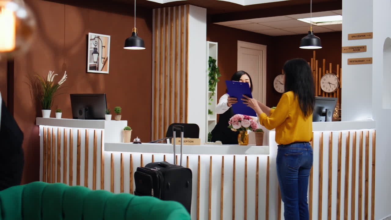 Viaggiatore asiatico che firma un assegno alla reception