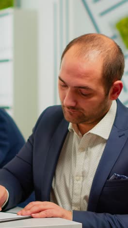 vertical video businessman reading paper document, discussing contract with confident partner
