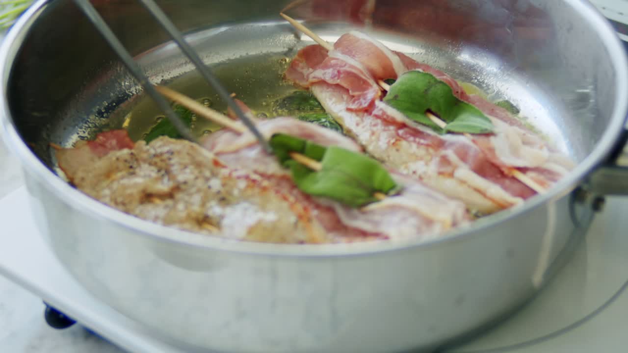 persona freyendo saltimbocca en palos de madera en una sartén