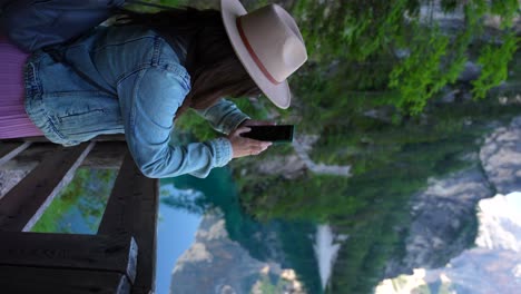 frau macht fotos mit einem smartphone in lago di braies, dolomiten, italien