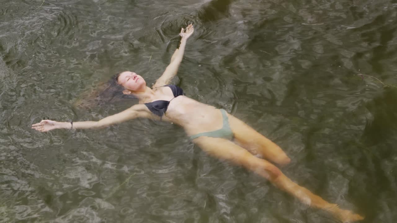 mujer caucásica pasando un buen rato en un viaje a las montañas, con traje de baño y flotando en