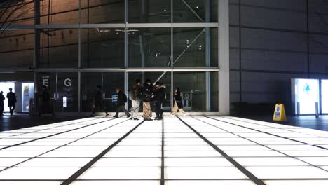 outside at night tokyo international forum light squares with commuters walking past.