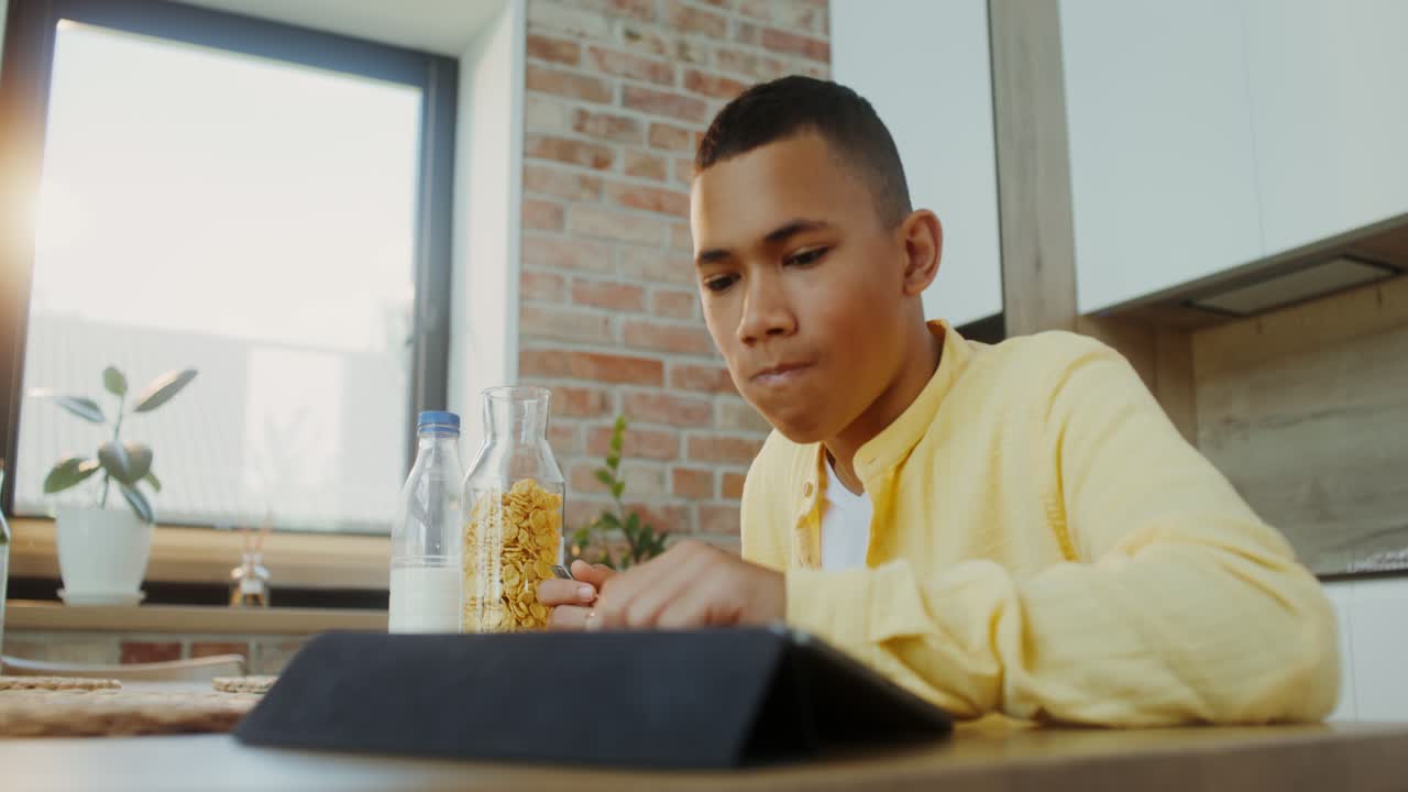 Teenager eating breakfast while using tablet