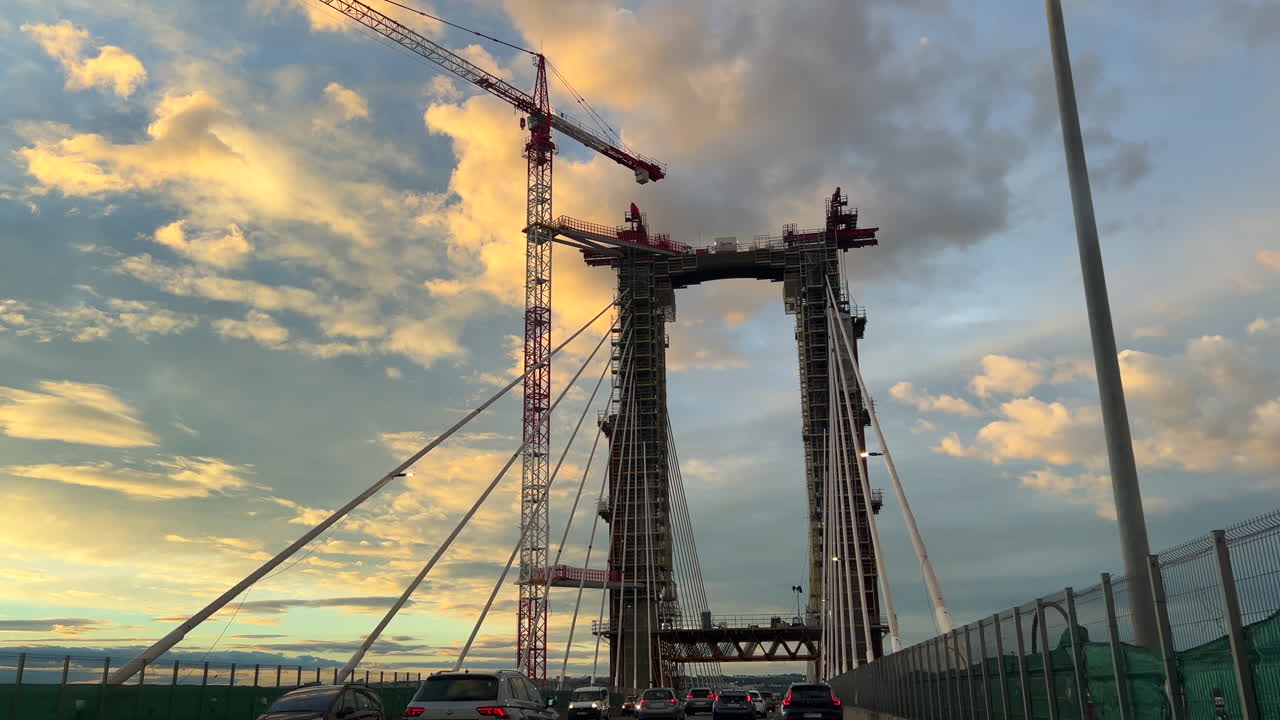 Cars driving over The Constitution of 1812 Bridge, La Pepa Bridge in the south of Spain, the Bay of Cadiz, blue sky and yellow clouds, new modern structure, 4K shot