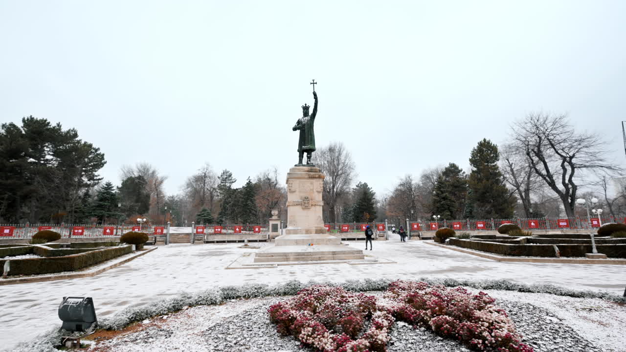 View of Stephen the Great monument during a snowfall in Chisinau, Moldova. Walking people, bare trees