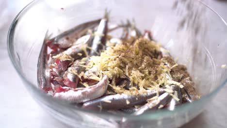 grate garlic in the bowl of sardines