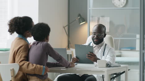 african american pediatrician giving health consultation to boy and his mom