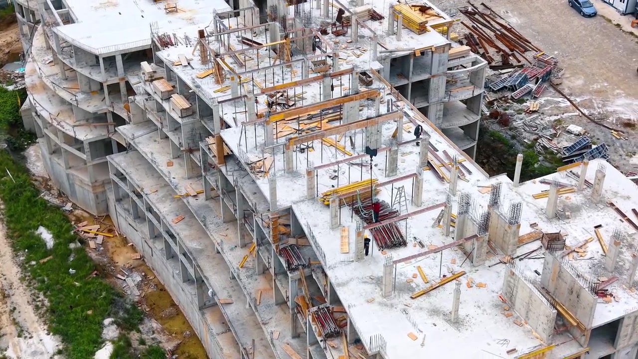 Construction workers building concrete floor reinforcement on high angle. High angle view of laborers working on the reinforced concrete deck of a building under construction.