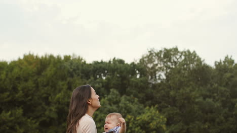 happy mother tossing up her cute toddler son in the park 1