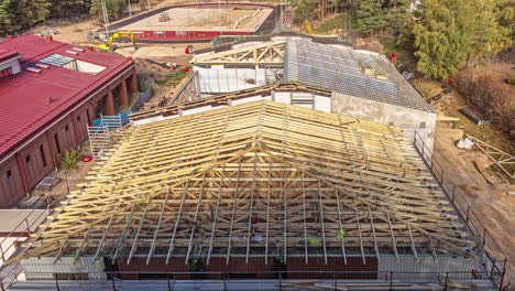 erecting a wooden frame roof over a newly constructed school sports facility and installing solar panels - time lapse