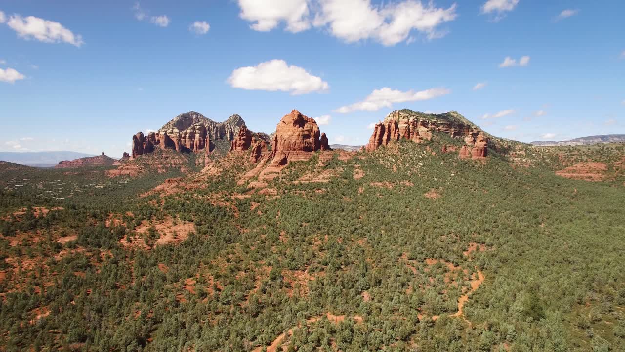 Aerial slow push in over pinion pine forest to large red rock butte.