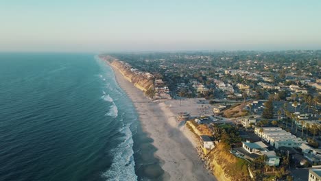 stunning wide aerial view of the california coastline at moonlight beach at a warm, clear and sunny day with calm blue ocean near san diego - 4k footage