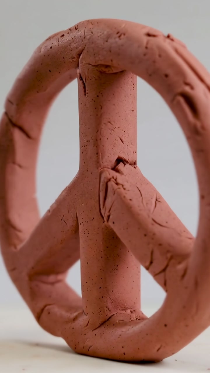 Textured Clay Peace Sign Rotating on White Background