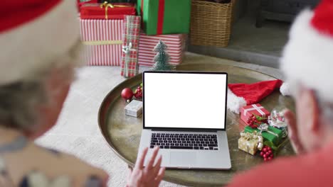 Pareja-Caucásica-Mayor-Con-Sombreros-De-Santa-Haciendo-Videollamada-Navideña-Con-Computadora-Portátil,-Con-Espacio-Para-Copiar-En-La-Pantalla