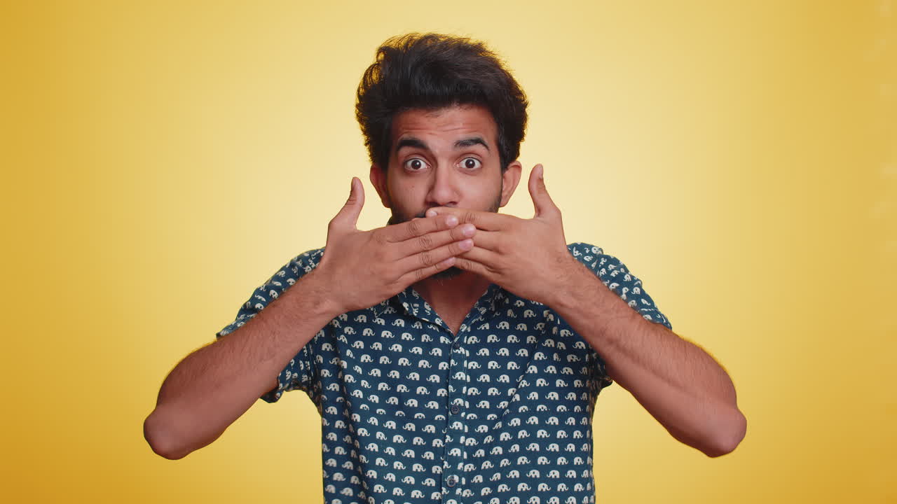 Young indian man presses finger to lips makes silence gesture sign do not tells secret, stop gossip