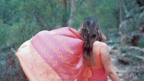 Back-View-Of-A-Woman-In-Red-Sari-Walking-Through-The-Forest-At-Daytime---medium-shot