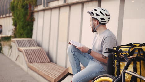 food delivery man reads a book while waiting for the next order