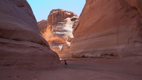 lonely female figure walking between sandstone cliffs in antelope slot canyon