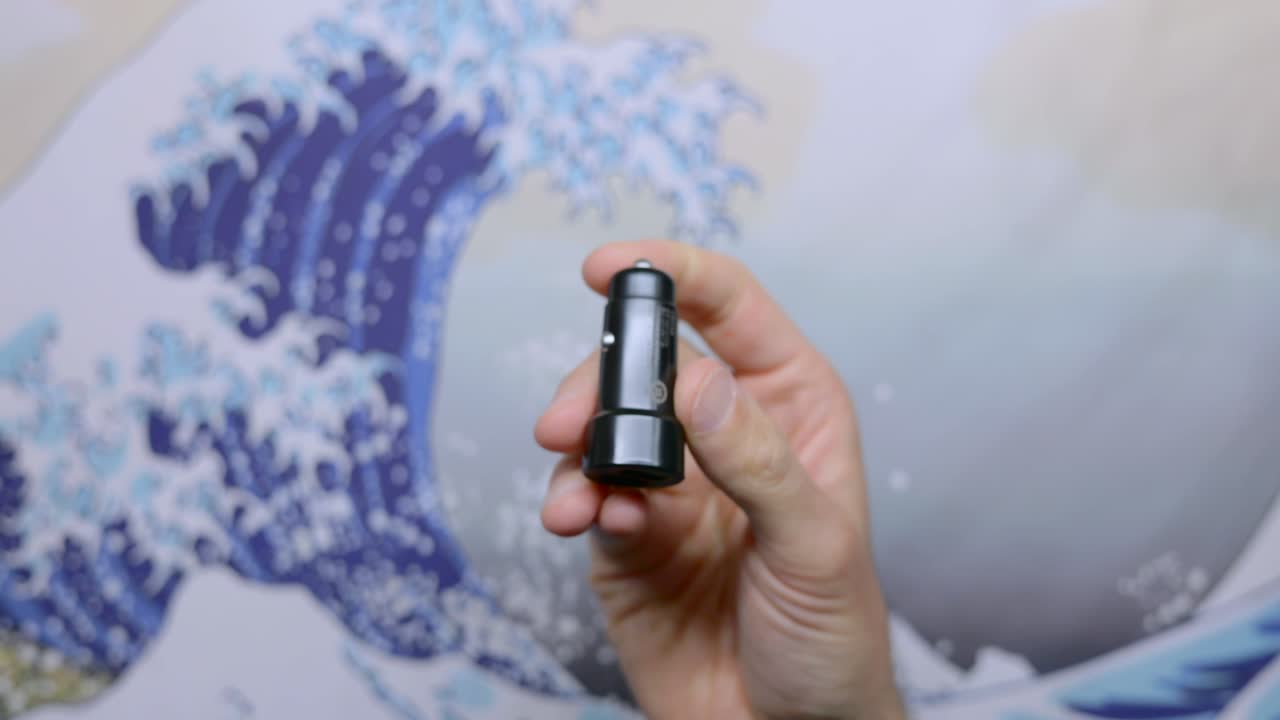 Hand holds a USB adapter accessory for a car cigarette lighter port