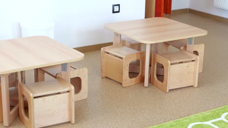 pair of small wooden tables, benches for students in kindergarten classroom