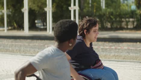 Happy-couple-using-wheelchair-walking-and-talking-outdoors