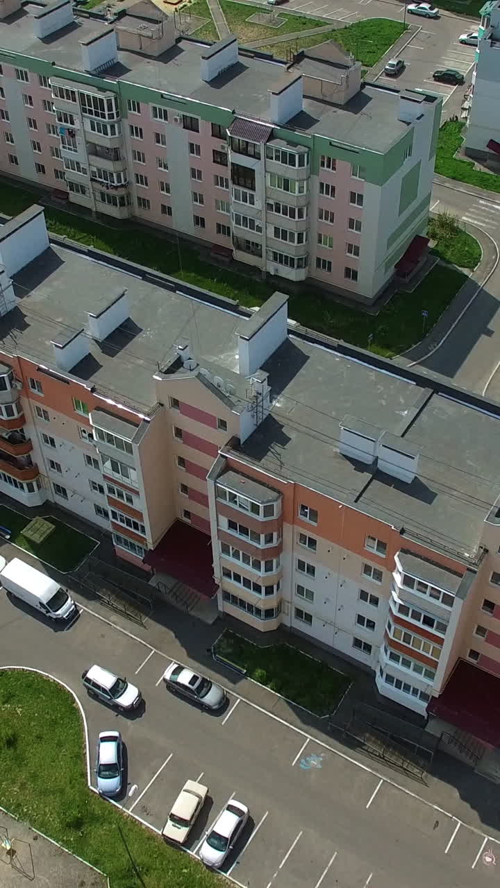 Flying forward over the new colorful buildings recently built in the residential area in the city. Nicely planned architectural buildings during the sunny day. Vertical video