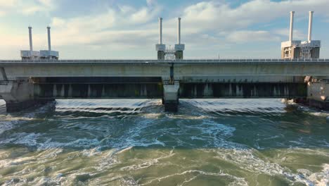 Luftaufnahme,-Die-An-Einem-Schönen-Sonnigen-Tag-Aus-Dem-Wasser-Herauszoomt,-Das-Durch-Das-Sturmflutwehr-Der-Ostufer-Schelde-In-Zeeland,-Niederlande,-Fließt