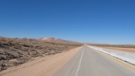 looking out the rear window in a car driving through the mojave desert's arid landscape