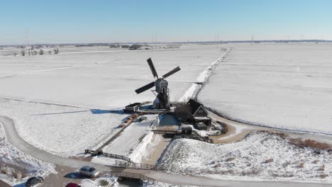 Aerial-shot-of-Dutch-windmill-in-white-snowy-countryside,-winter-landscape-scene