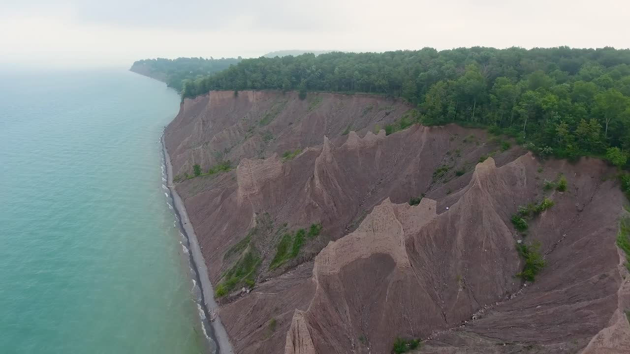 A 4K drone shot over the large clay formations of Chimney Bluffs State Park, on the water's edge of Lake Ontario, in the town of Huron, New York