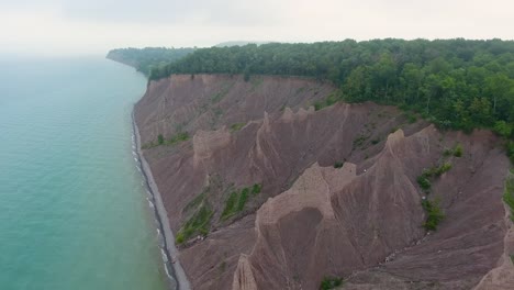 A-4K-drone-shot-over-the-large-clay-formations-of-Chimney-Bluffs-State-Park,-on-the-water's-edge-of-Lake-Ontario,-in-the-town-of-Huron,-New-York