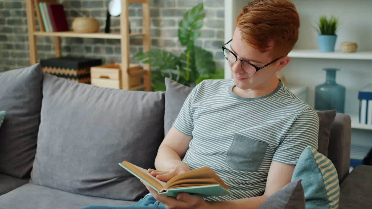 Young Man Reading a Book on a Couch