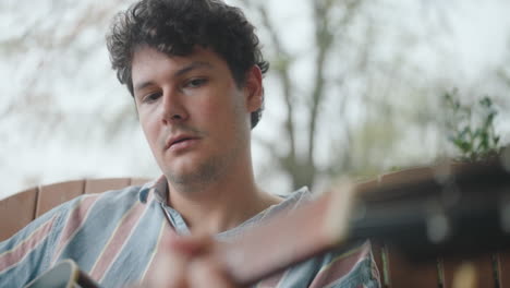 man playing acoustic guitar on a porch