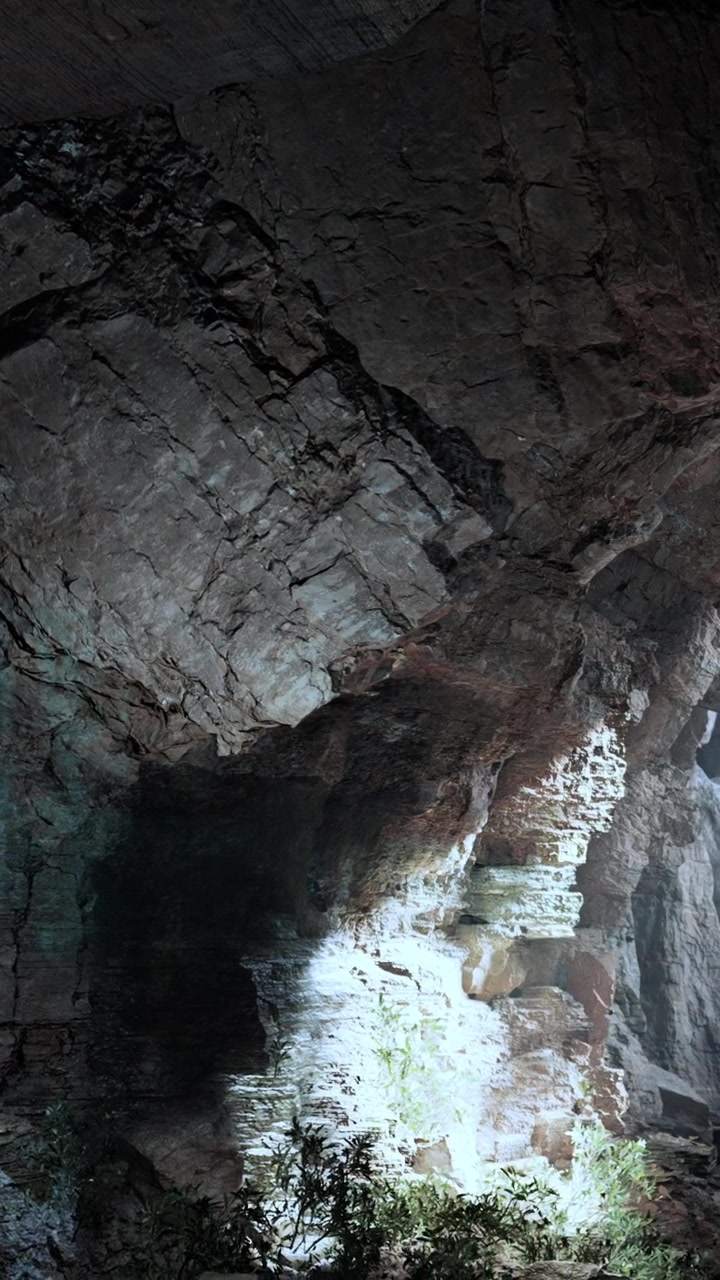 Visitatori esplorano una grotta profonda con interessanti formazioni rocciose e ombre.