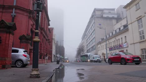 Fogbound-street-with-a-car-driving-past-and-person-walking-away