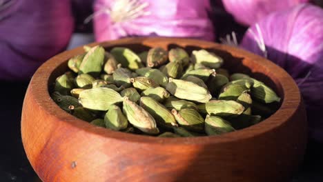 close up of green cardamom pods in a wooden bowl