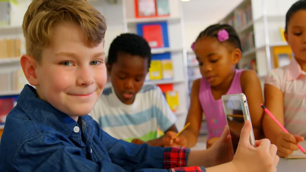 Caucasian schoolboy using digital tablet in school library 4k