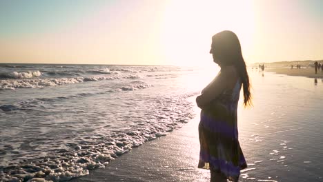 a woman facing the ocean while thinking of something during sunset. static shot