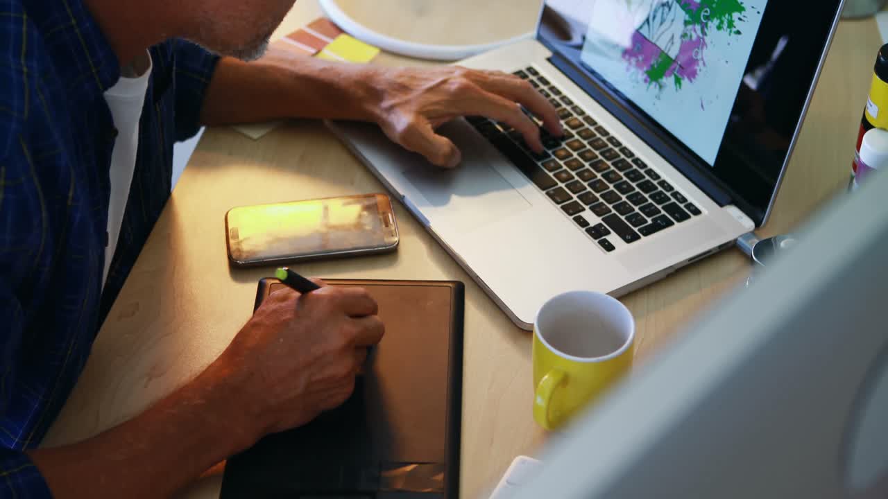 hombre usando tableta gráfica mientras trabaja en una computadora portátil 4k