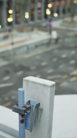 a close-up of a metal fence with a blurred city background