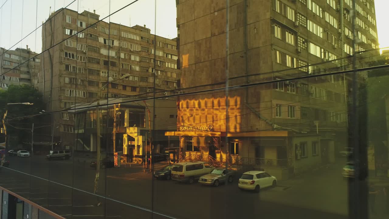 벽에 거울 창문이 있는 비즈니스 디스트릭트 빌딩이나 쇼핑몰의 4k 외관, 빛, 거울 벽에 있는 도시, 자동차 및 타워의 반사, 드론 카메라 이동