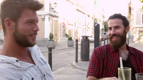 two male friends talking at a table outside a cafe, ibiza, shot on r3d