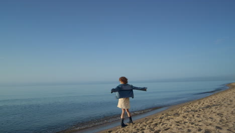 happy woman dancing at sea shore. playful girl turning around on beach