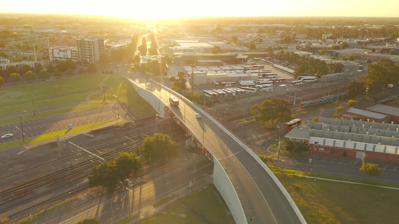 Aerial View of City at Sunset with Bus Depot and Train Tracks