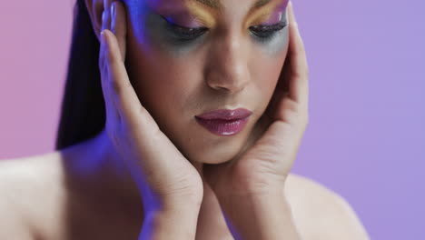 biracial woman with black hair and make up touching her face, copy space, slow motion